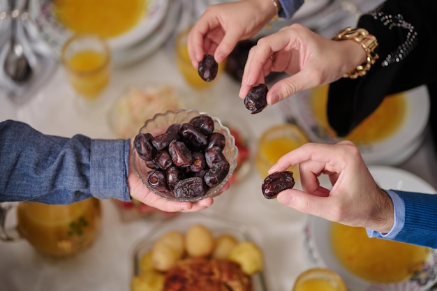 Heureuse famille musulmane ayant un dîner iftar pour rompre le jeûne pendant la table à manger du Ramadan à la maison