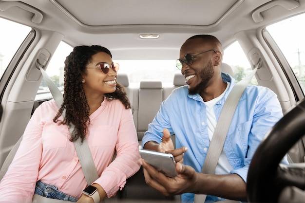 Heureuse famille noire conduisant une voiture et utilisant un smartphone