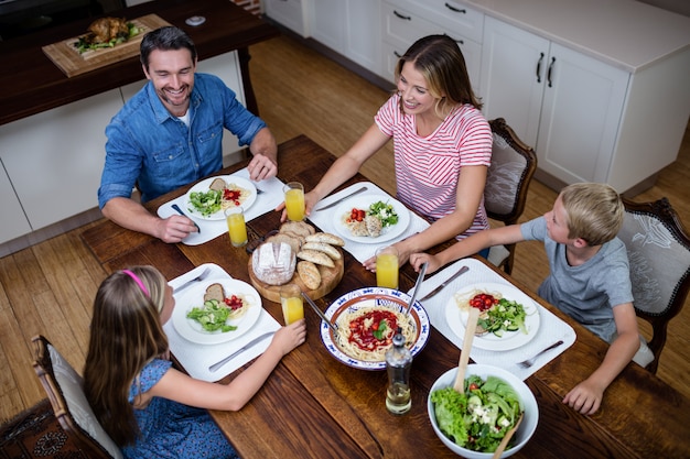 Photo heureuse famille parler les uns aux autres tout en prenant un repas dans la cuisine