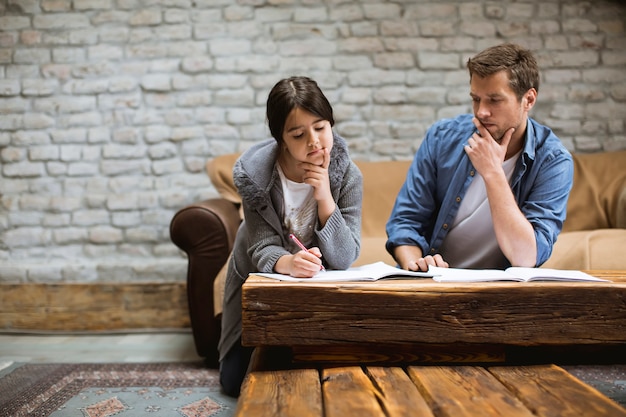 Heureuse famille père et fille à faire leurs devoirs à la maison