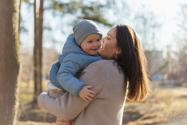 Heureuse famille en plein air mère embrassant son enfant maman en plein air soulevant dans l'air petit fils enfant en bas âge