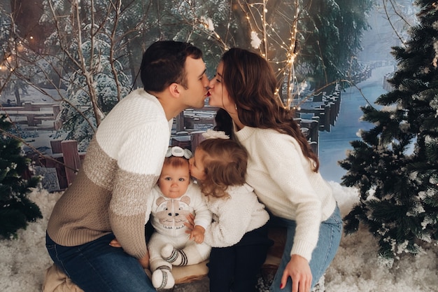 Heureuse famille de quatre personnes avec des arbres de Noël et beaucoup de neige