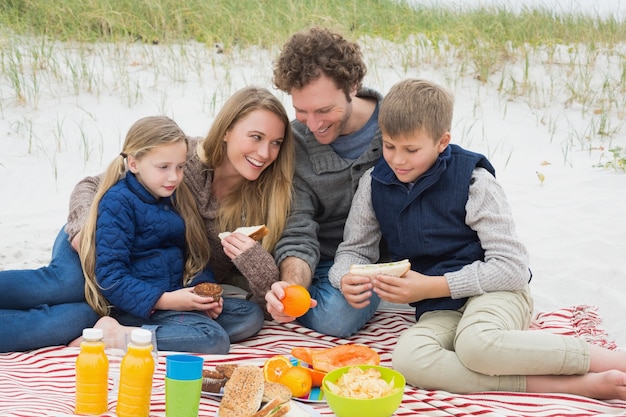 Heureuse famille de quatre personnes à un pique-nique de plage