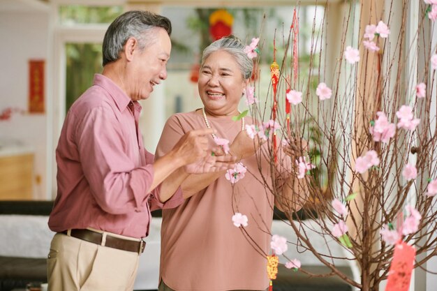 Heureuse famille senior décorant la maison pour le concept de joyeuses fêtes du nouvel an chinois