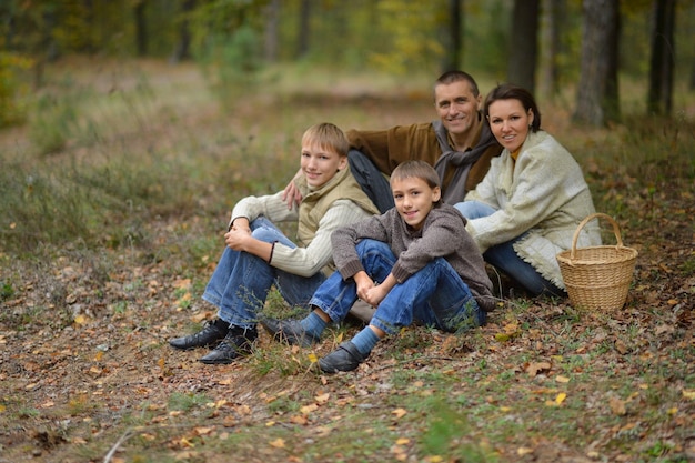 Heureuse famille souriante dans la forêt d'automne assis