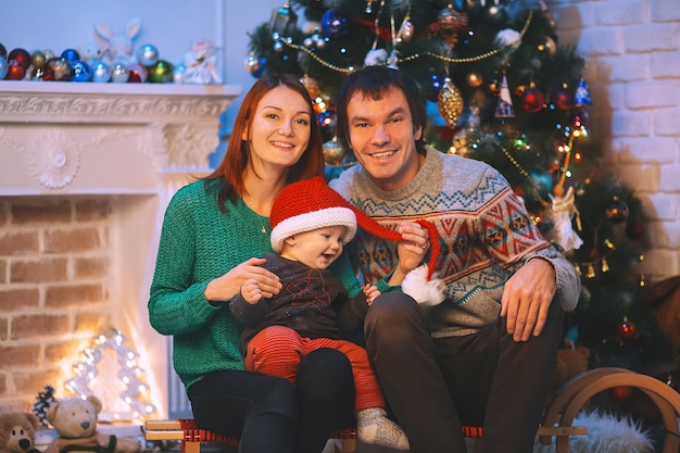 Heureuse famille souriante à l'intérieur d'une maison sur fond d'arbre de Noël avec des cadeaux