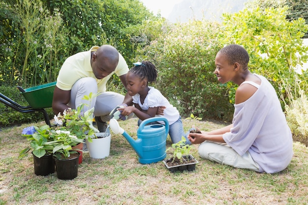 Heureuse famille souriante plante une fleurs ensemble