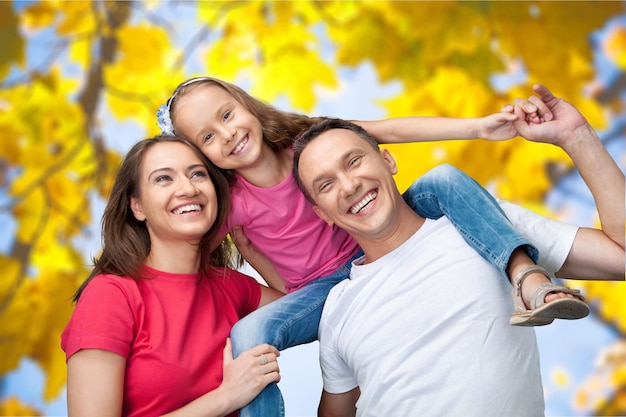 Heureuse famille souriante avec sa fille sur fond d'arbres d'automne