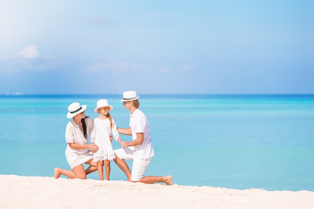 Heureuse famille de trois personnes s'amusant ensemble sur la plage