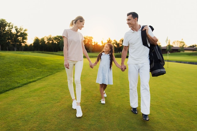 Heureuse famille unie de golfeurs se promène après le match.