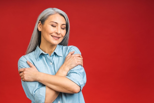 Heureuse femme d'affaires d'âge mûr mature et élégante souriante debout isolée sur fond rouge souriante confiante et joyeuse dame d'âge moyen copie espace