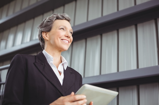 Heureuse femme d'affaires à l'aide de tablette numérique au bureau