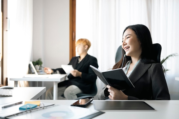 Heureuse femme d'affaires asiatique assise à son bureau.