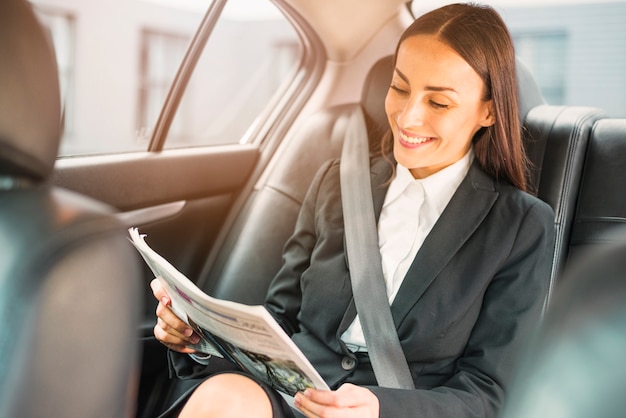 Heureuse Femme D'affaires Assis à L'intérieur D'un Journal De Lecture De Voiture