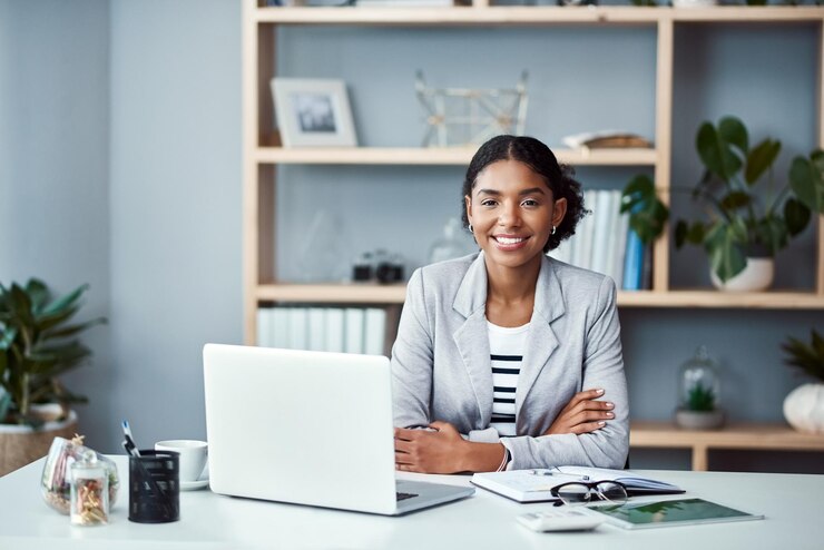 Photo heureuse femme d'affaires confiante et prospère prête à diriger une start-up et à commencer à travailler sur un ordinateur portable fier et puissant pdg ou entrepreneur afro-américain assis à un bureau