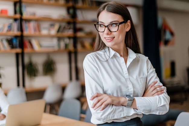 Heureuse femme d'affaires dans des verres à la recherche de côté dans le bureau