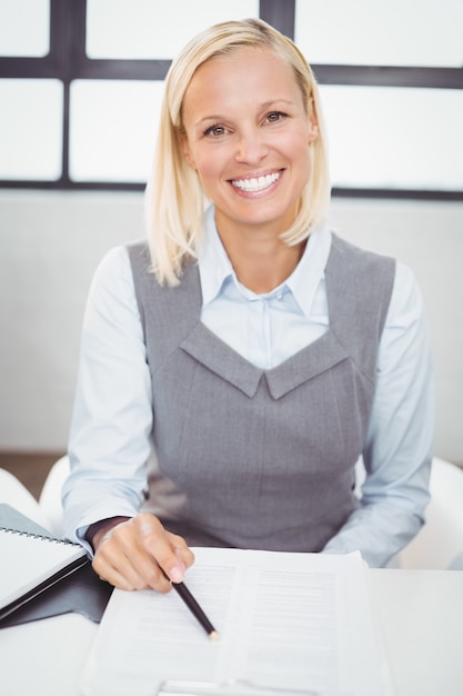 Heureuse femme d'affaires avec des documents assis au bureau