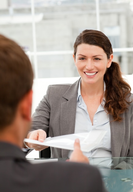 Heureuse femme d&#39;affaires donnant un papier à un collègue masculin lors d&#39;une réunion