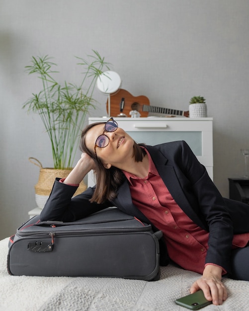 Une heureuse femme d'affaires du millénaire européen fait ses bagages pour la valise d'emballage de route pour une entreprise