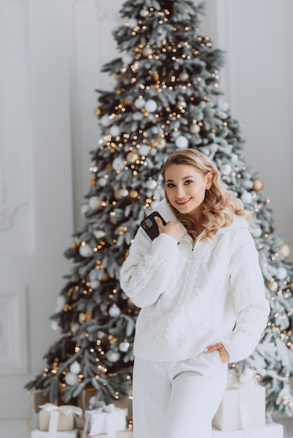 Heureuse femme d'affaires européenne parlant au téléphone mobile avec un client sur le lieu de travail avec un arbre de Noël décoré derrière une femme souriante travaillant au bureau à domicile pendant les vacances d'hiver Mise au point sélective douce