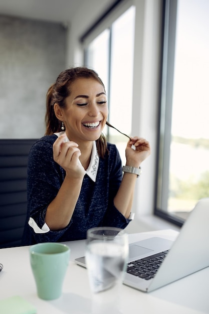 Heureuse femme d'affaires flirtant lors d'un appel vidéo au bureau