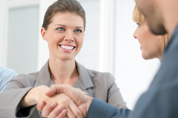 Heureuse femme d'affaires souriante se serrant la main après une réunion d'affaires