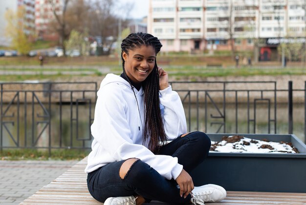 L'heureuse femme afro-américaine dans le parc sur un banc