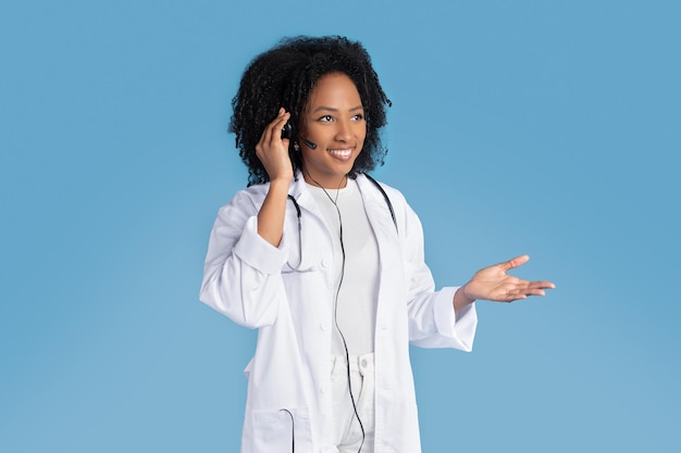 Heureuse femme afro-américaine millénaire en blouse blanche avec un casque stéthoscope sur vide