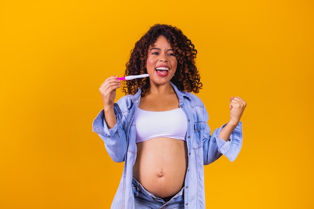 Heureuse femme afro avec un test de grossesse. femme célébrant sa grossesse