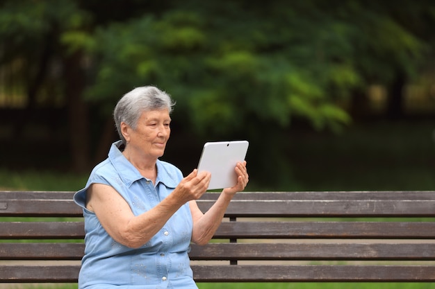 Heureuse femme âgée handicapée assise sur un banc dans le parc