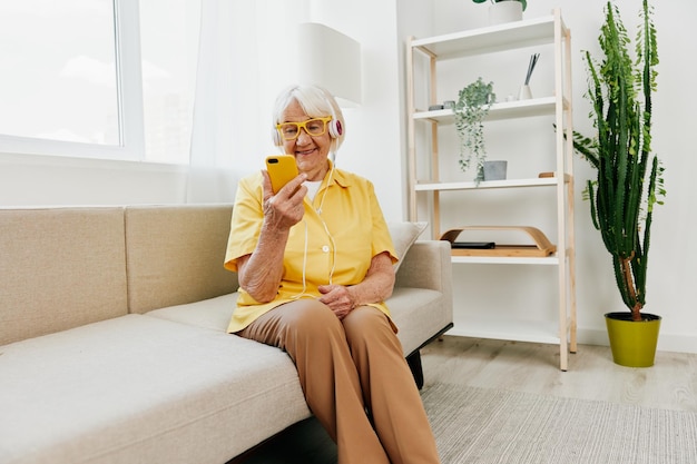 Heureuse femme âgée regardant dans la technologie de sourire d'appel vidéo téléphonique pour la communication en ligne de style de vie intérieur moderne et lumineux