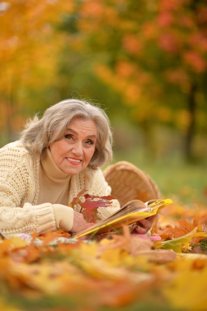 Heureuse femme âgée se reposant dans un parc automnal