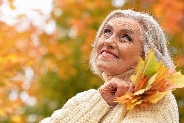 Heureuse femme âgée souriante et posant dans le parc d'automne