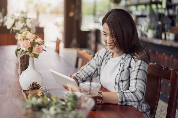 Heureuse femme à l&#39;aide de tablette numérique au café