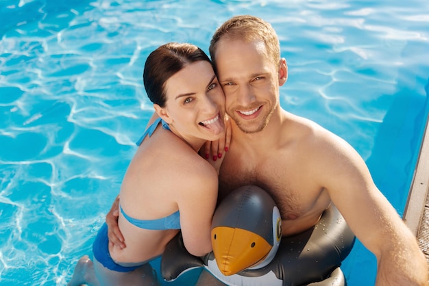 Heureuse femme aimante passer du temps avec son mari près de la piscine du complexe