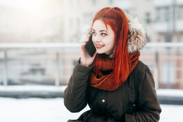 Heureuse femme appelant sur le téléphone mobile dans la rue en hiver