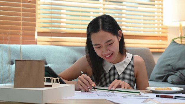 Heureuse femme architecte travaillant sur un projet à la maison