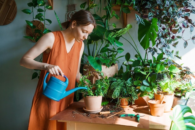 Heureuse femme arrosant dans la chambre gros plan arroser soigneusement les plantes en utilisant l'arrosage