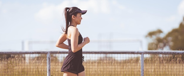 Heureuse femme asiatique adulte souriante faisant du jogging en plein air dans le parc de la ville au soleil belle journée d'été. Heureuse femme mûre détendue faisant du jogging pour vivre un mode de vie actif et sain