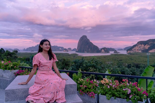 Heureuse femme asiatique assise devant la belle île de montagne avec un ciel crépusculaire à Sametnangshe