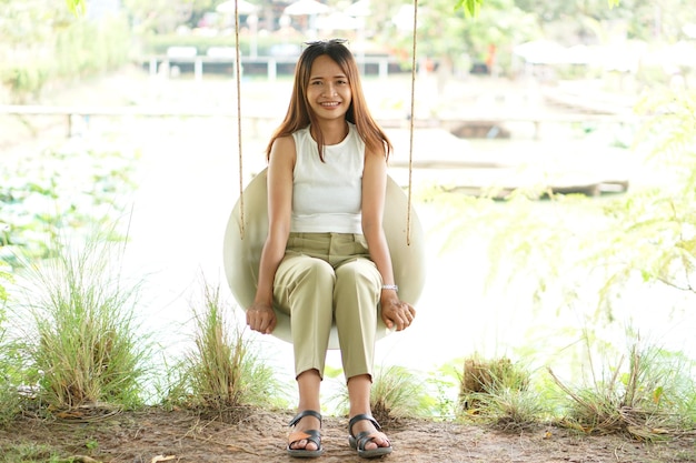 Heureuse femme asiatique sur une balançoire dans le parc