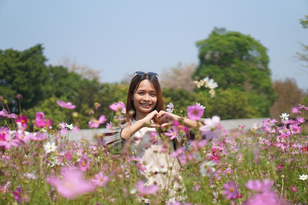 Heureuse femme asiatique dans le jardin de fleurs du cosmos