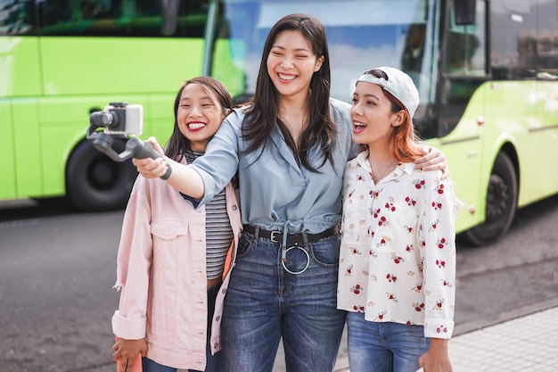 Heureuse femme asiatique faisant une vidéo à la gare routière de la ville