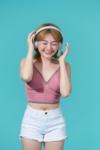 Heureuse femme asiatique joyeuse portant des écouteurs sans fil, écouter de la musique depuis un smartphone