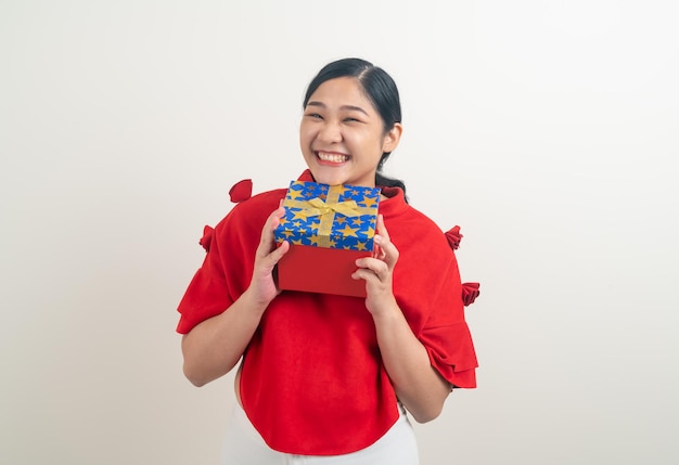 Heureuse femme asiatique portant une chemise rouge avec une boîte-cadeau à portée de main pour le festival de Noël