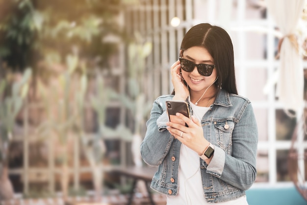 Heureuse femme asiatique utilisant un téléphone pour écouter de la musique.