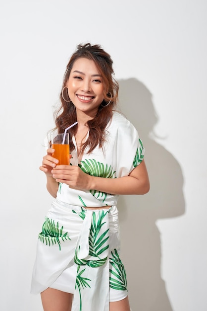 Heureuse femme asiatique en vêtements décontractés d'été avec un verre de boisson de jus de fruits frais