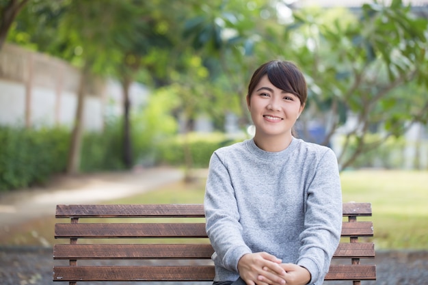 Heureuse femme assise sur le banc au parc