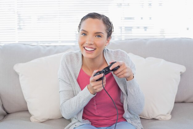 Heureuse femme assise sur un canapé à jouer à des jeux vidéo