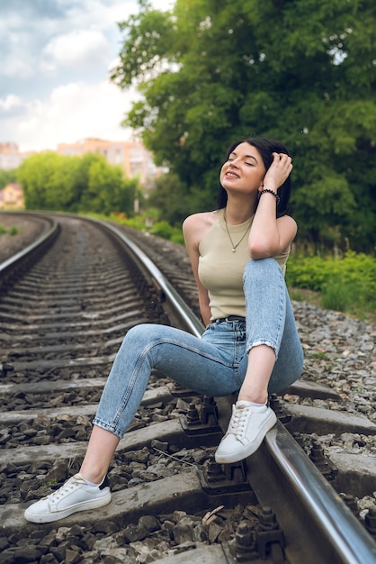 Heureuse femme assise sur le chemin de fer en tissu d'été, voies ferrées, mode de vie